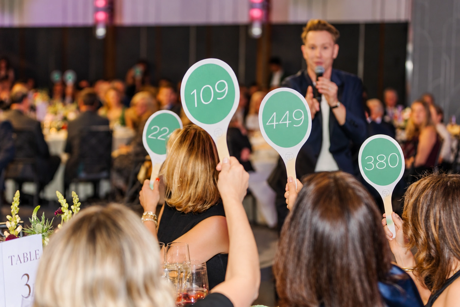 Guests raising auction paddles during a gala fundraiser