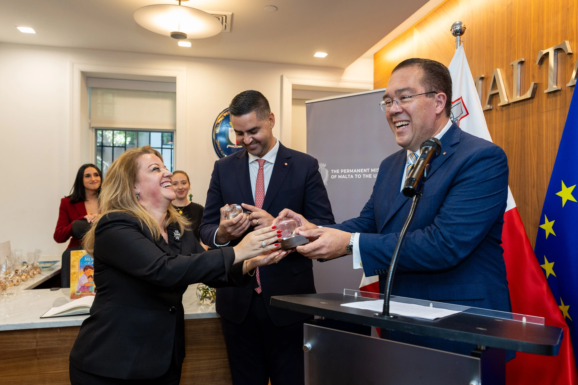 An award presentation at an event with Malta and European Union flags