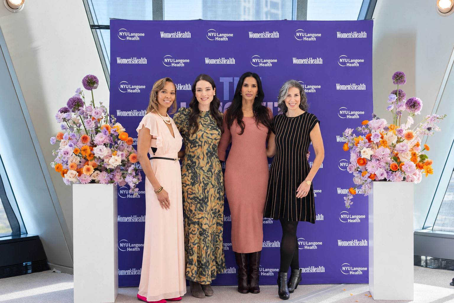 Four guests posing at the NYU Langone Health and Women’s Health backdrop