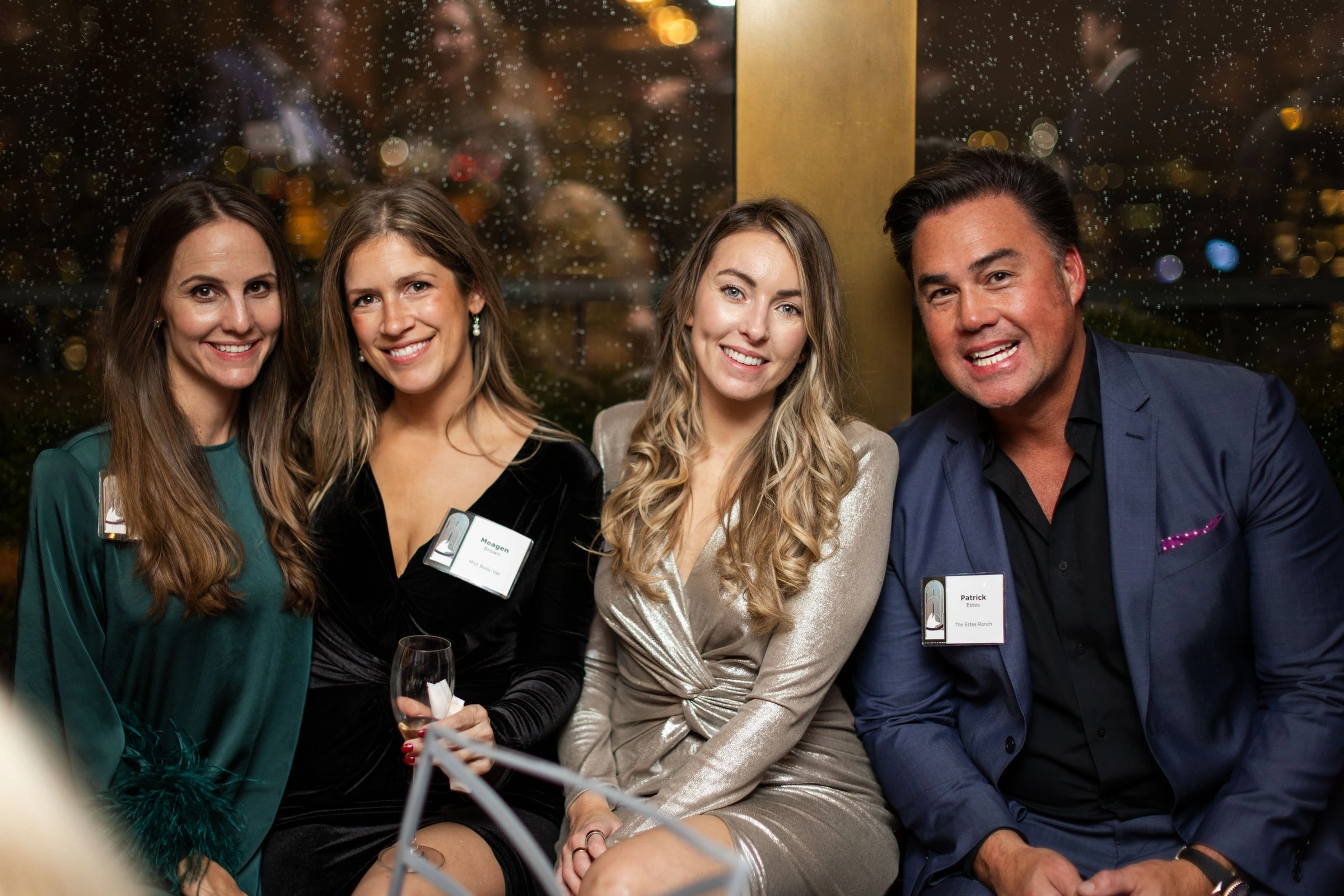 Three women and a man posing together at an evening reception
