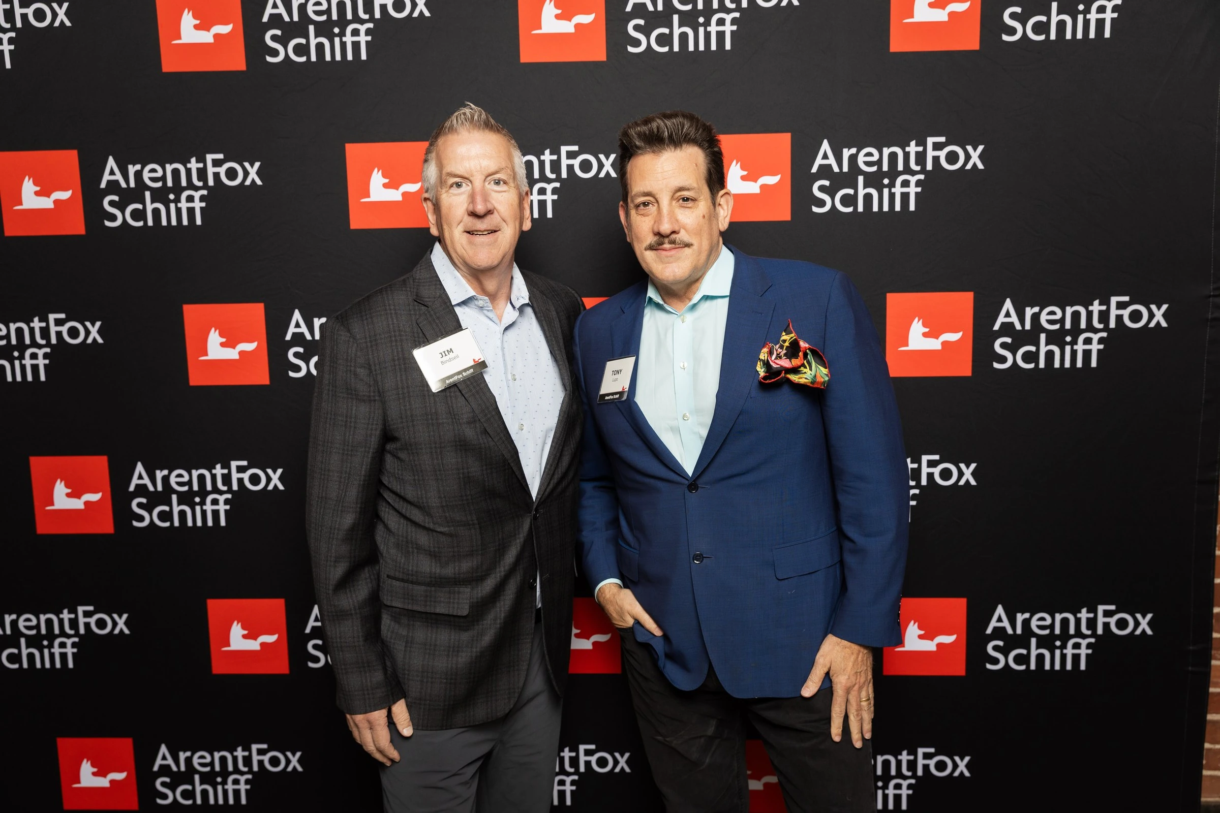 Two men posing at the ArentFox Schiff event backdrop