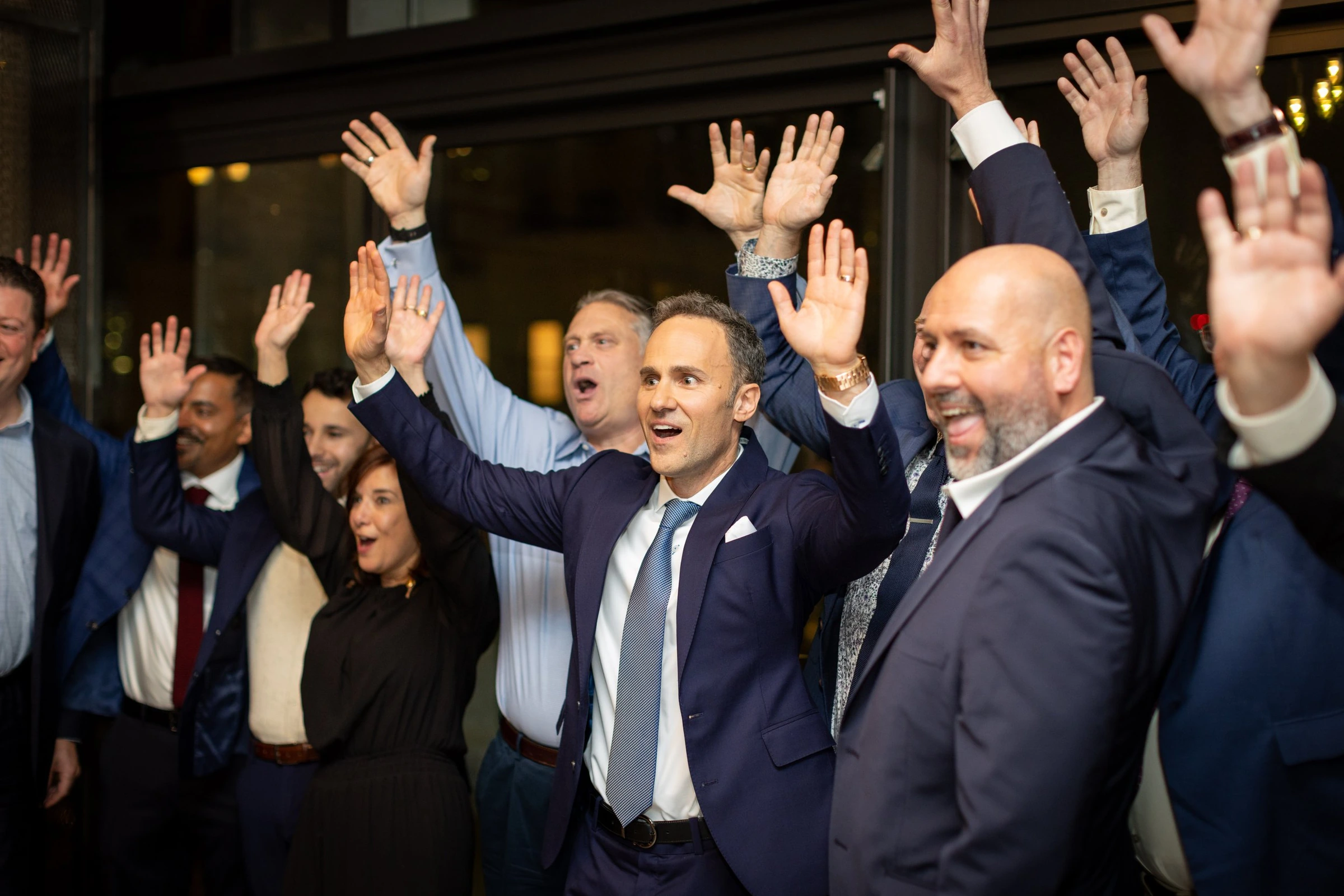 Guests in suits raising their hands during a company celebration
