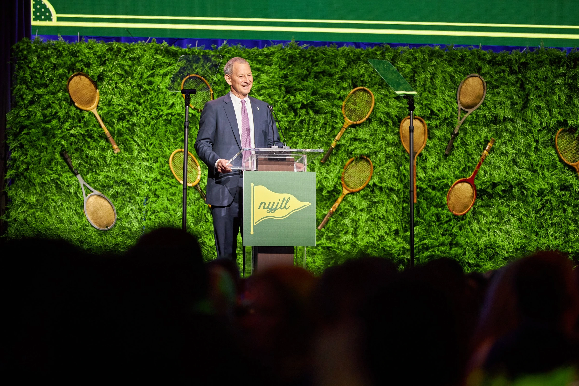 A speaker at the NYJTL podium with the audience in the foreground