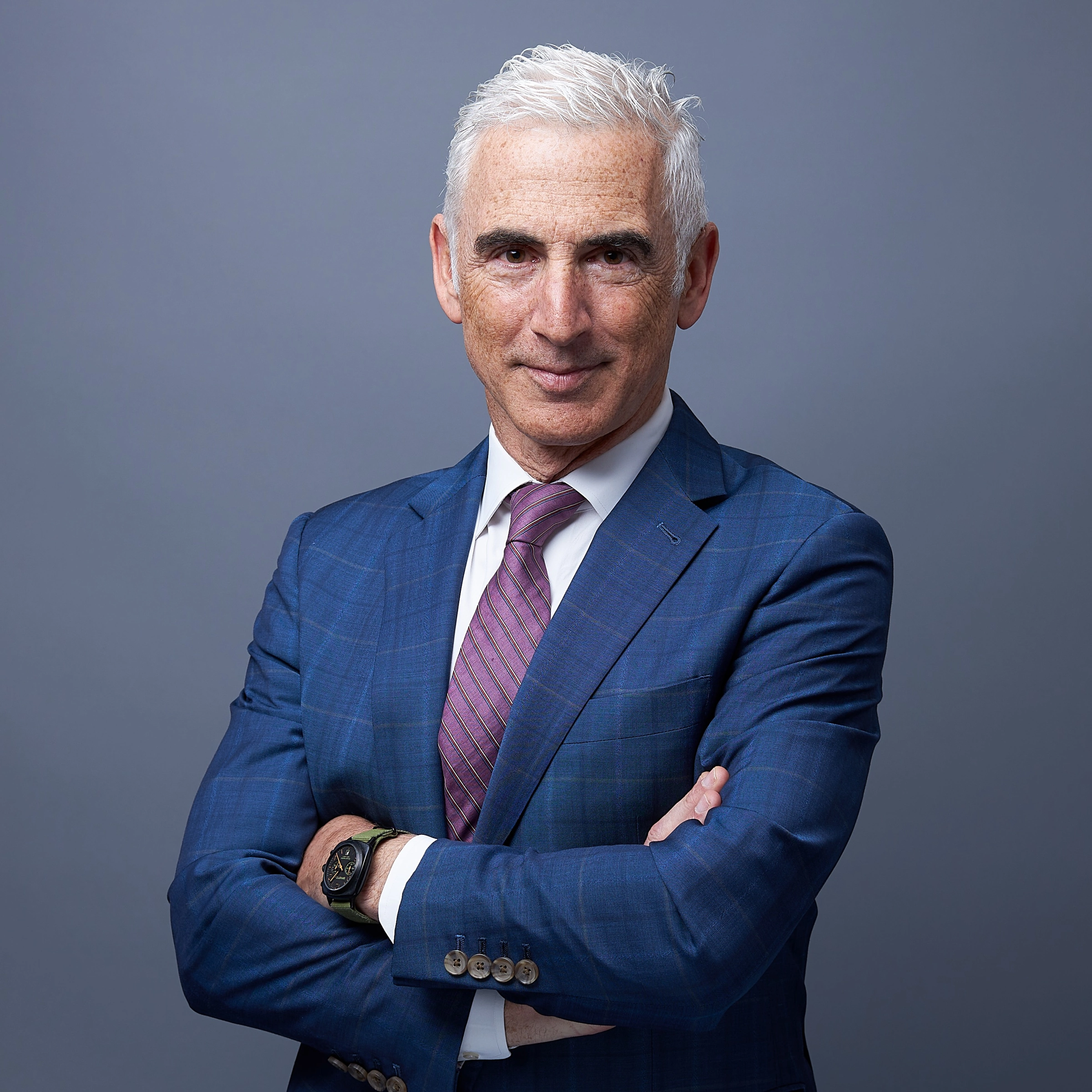 Executive portrait of a silver-haired man in a blue suit